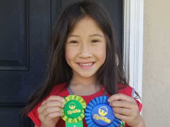 Katie, an Awana kid, with her club award ribbons